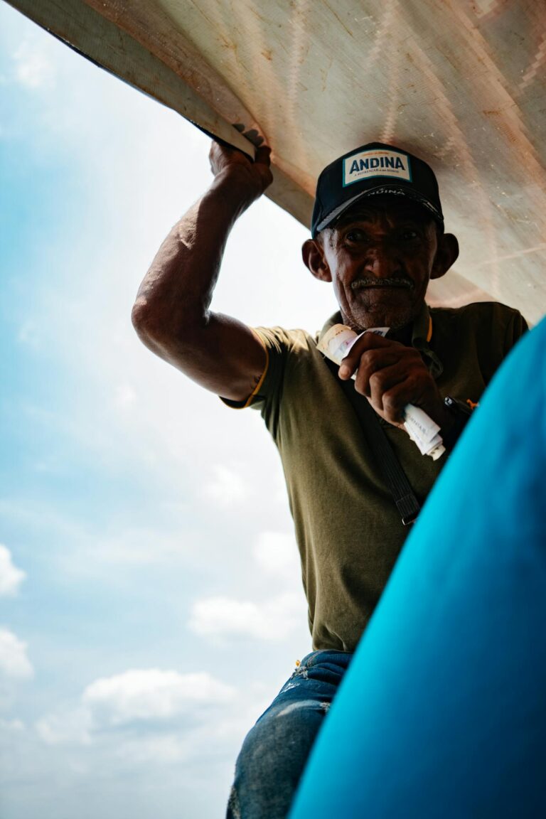 Portrait of an elderly man holding a boat sail, set against a bright sky in Concordia, Colombia.